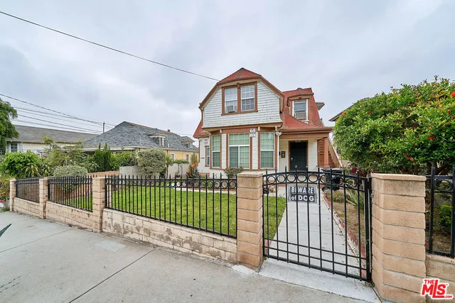 a view of a house with a small yard and wooden fence