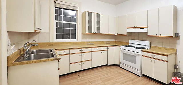 a kitchen with granite countertop a sink a stove and cabinets