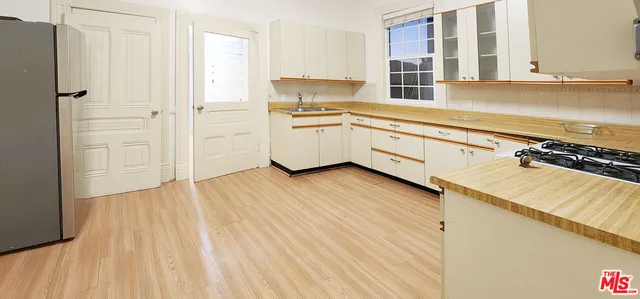 a kitchen with granite countertop a stove a sink and white cabinets with wooden floor