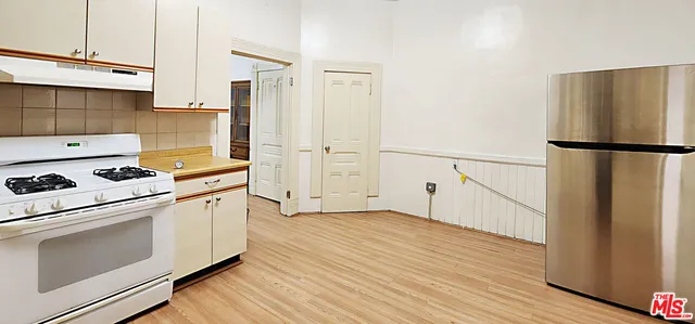 a kitchen with a refrigerator a stove top oven and wooden floor