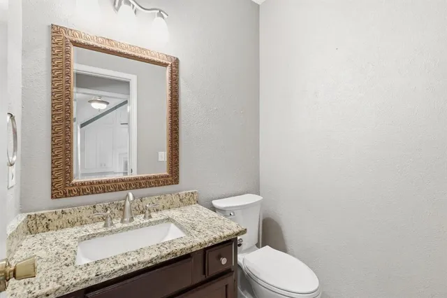 a bathroom with a granite countertop toilet sink and mirror