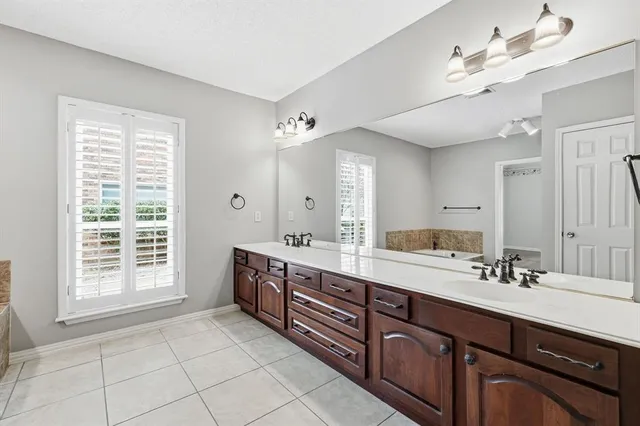 a spacious bathroom with a double vanity sink a mirror and a bathtub