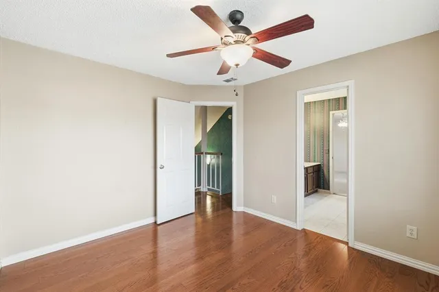 an empty room with wooden floor and a ceiling fan