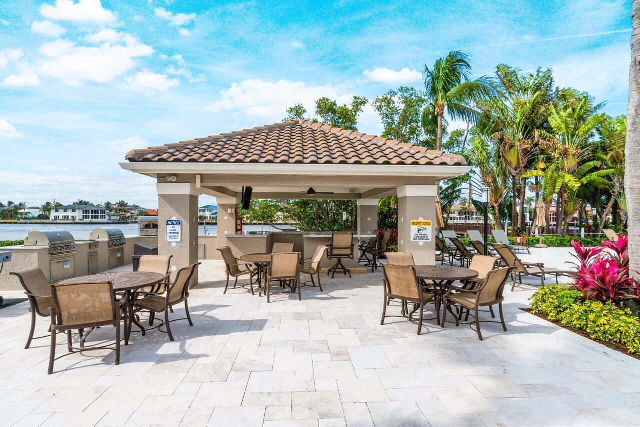 3594 South Ocean Boulevard, Unit 205 Highland Beach, FL 33487 - Photo 32 of 44 a view of a patio with table and chairs potted plants and palm trees