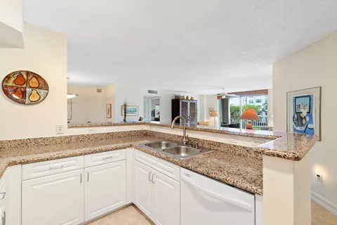 a kitchen with stainless steel appliances granite countertop a sink and a white countertops with wooden floor