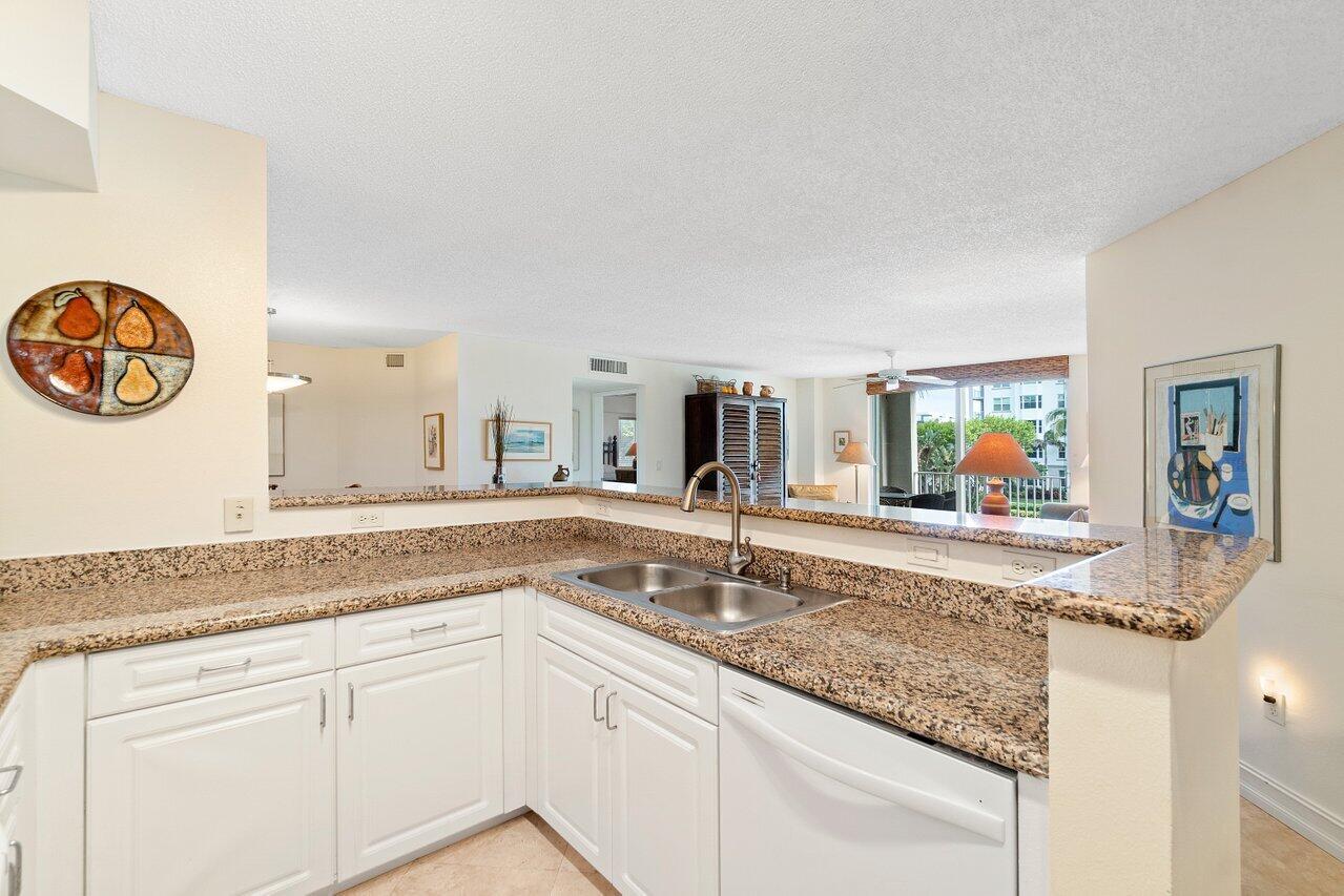 3594 South Ocean Boulevard, Unit 205 Highland Beach, FL 33487 - Photo 10 of 44 a kitchen with stainless steel appliances granite countertop a sink and a white countertops with wooden floor