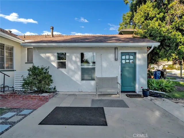 a view of a white house with large windows and potted plants