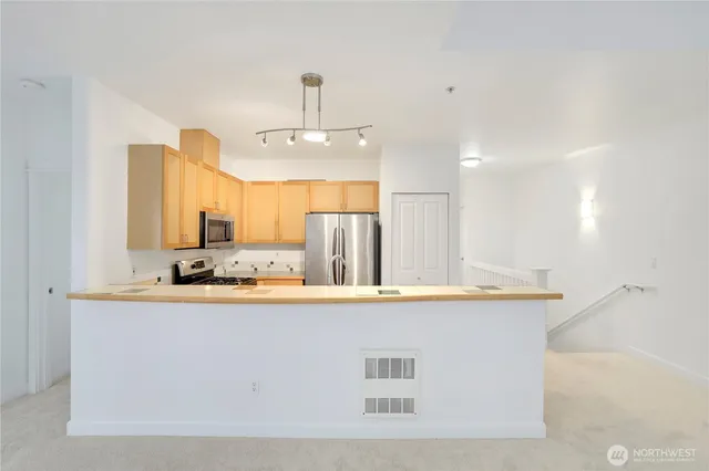 a view of a kitchen with kitchen island a sink a stove and a refrigerator