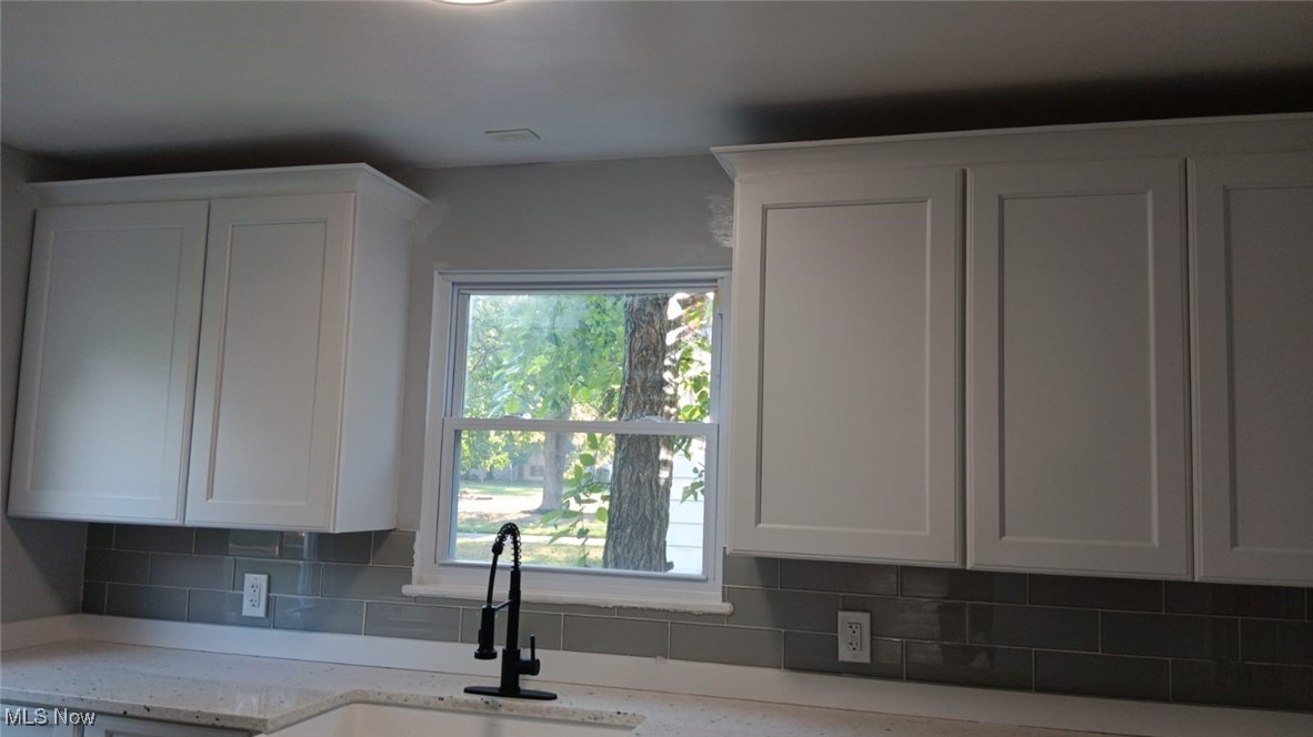 3999 Lancaster Road South Euclid, OH 44121 - Photo 16 of 17 Kitchen with light stone countertops, white cabinetry, sink, and tasteful backsplash