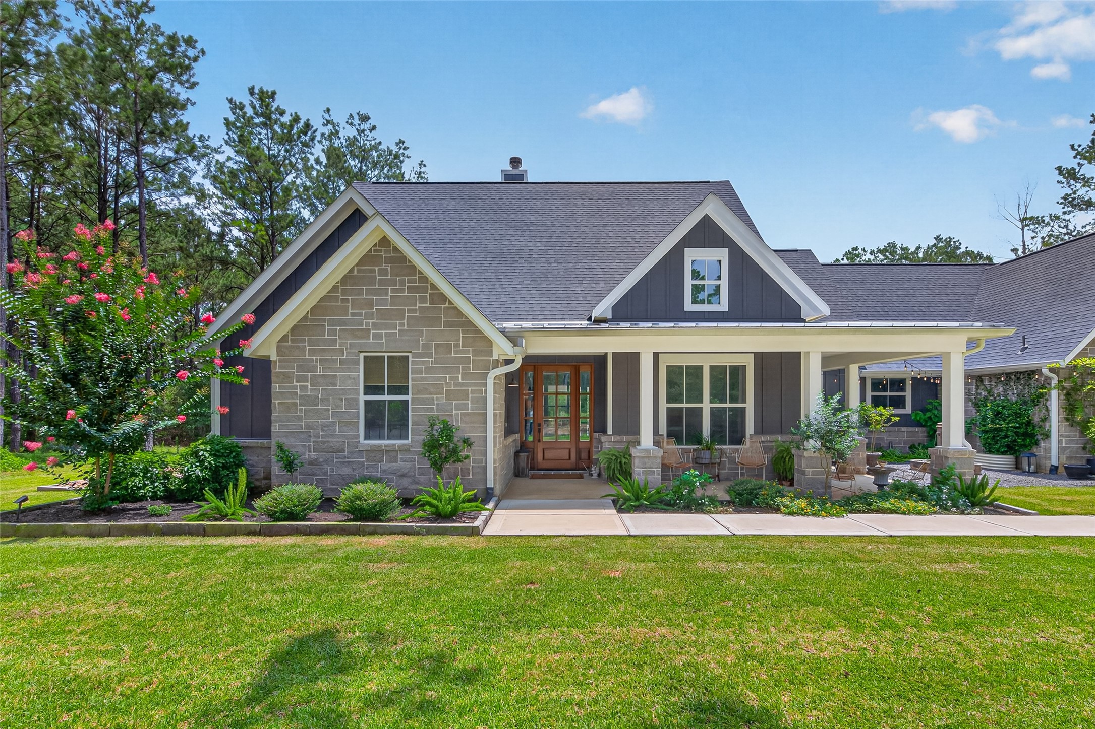 10915 Ruger Road Willis, TX 77378 - Photo 2 of 50 This modern farmhouse blends rustic charm with contemporary elegance, featuring a welcoming porch, stylish stone accents, and lush landscaping, set against a serene wooded backdrop.
