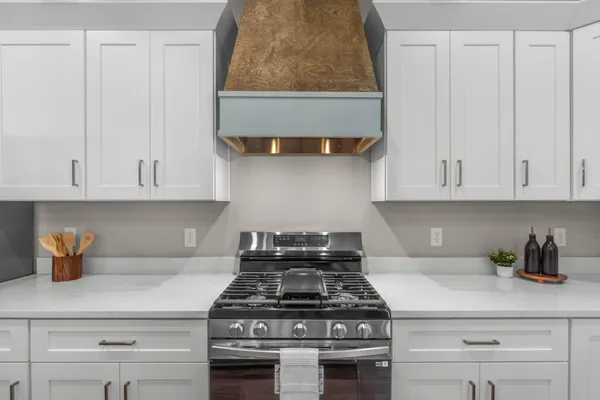 a kitchen with stainless steel appliances granite countertop a stove a white cabinet and a granite countertops with wooden floor
