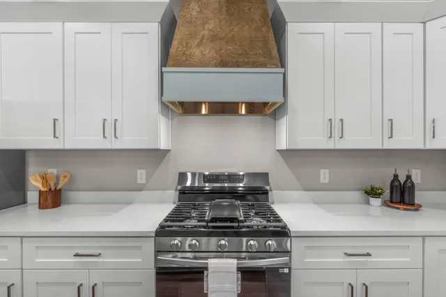 a kitchen with stainless steel appliances granite countertop a stove a white cabinet and a granite countertops with wooden floor