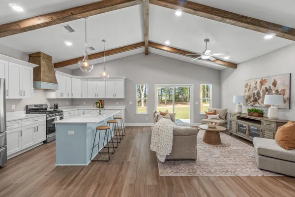 a large kitchen with cabinets chairs and wooden floor