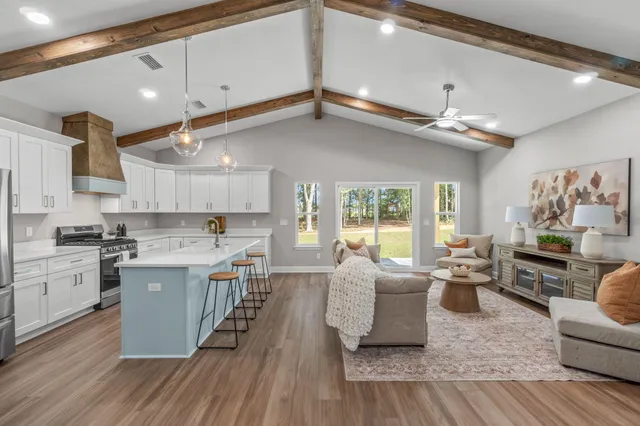 a large kitchen with cabinets chairs and wooden floor