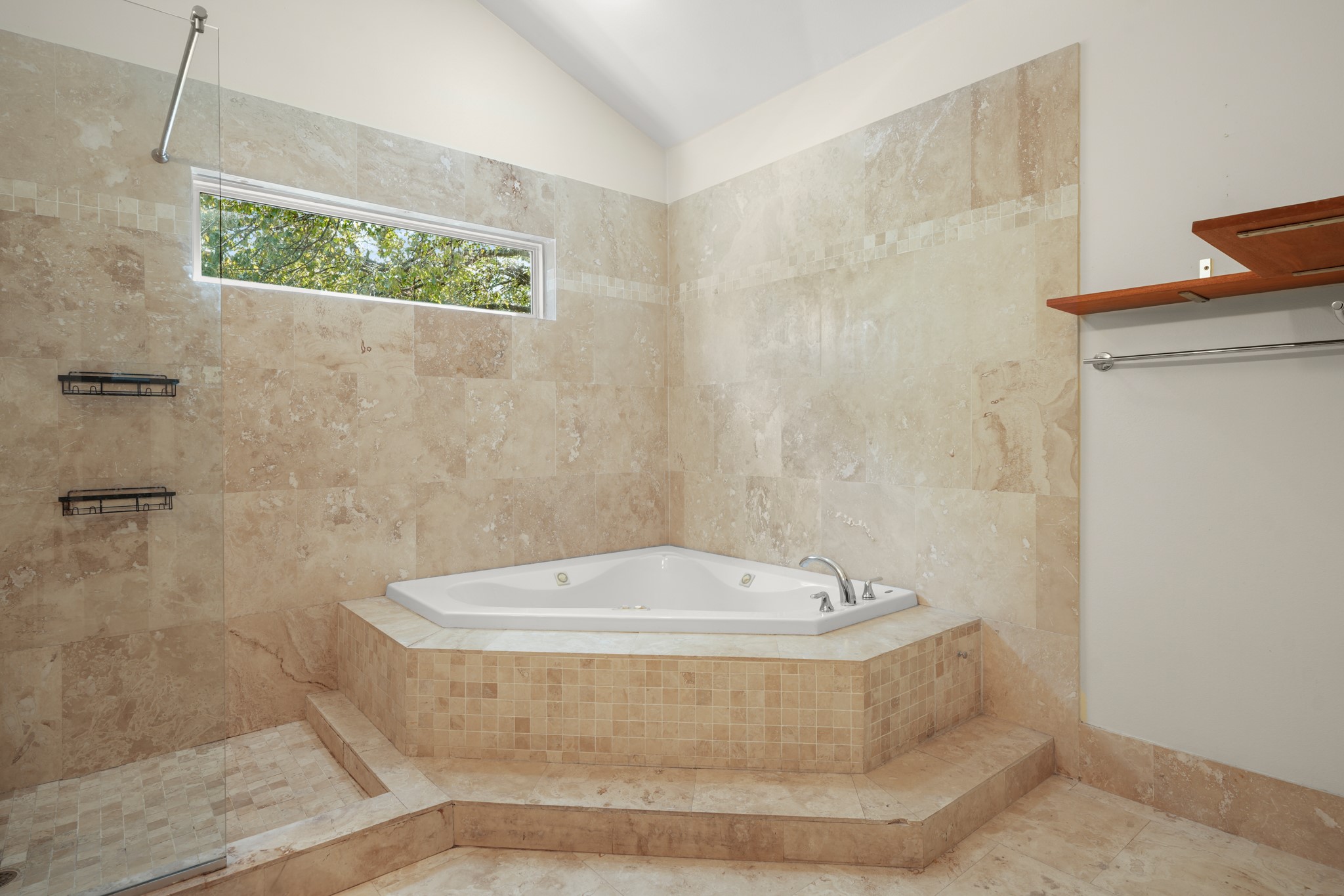2501 Del Curto Road Austin, TX 78704 - Photo 19 of 26 Natural stone tiling surrounds a deep soaking tub nestled below a high vaulted ceiling.
