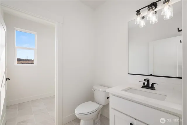 a bathroom with a granite countertop sink a toilet and with mirror
