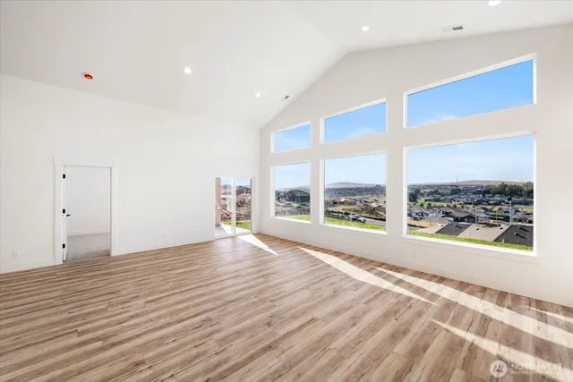 a view of an empty room with a window and wooden floor
