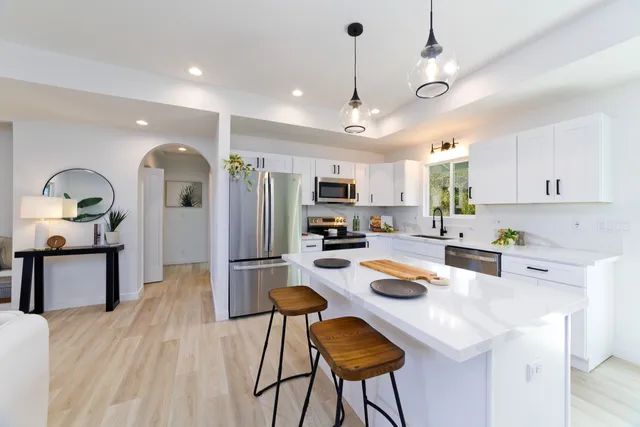 a kitchen with a refrigerator a stove a sink dishwasher a oven with a dining table and chairs with wooden floor