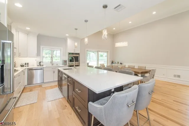 a large kitchen with kitchen island a stove a sink a refrigerator and a dining table with wooden floor