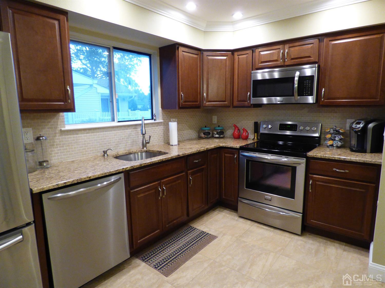797B Sparta Road, Unit 797A Monroe Township, NJ 08831 - Photo 14 of 25 a kitchen with stainless steel appliances granite countertop wooden cabinets stove top oven and sink