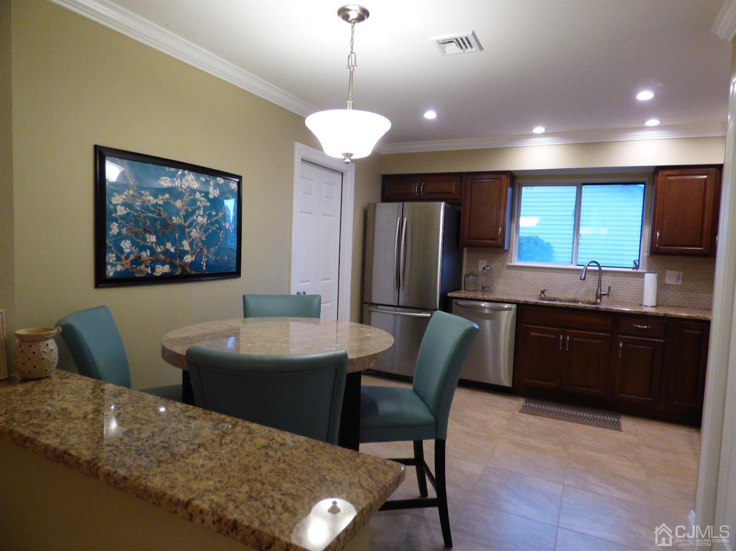 797B Sparta Road, Unit 797A Monroe Township, NJ 08831 - Photo 15 of 25 a kitchen with a table chairs refrigerator and microwave