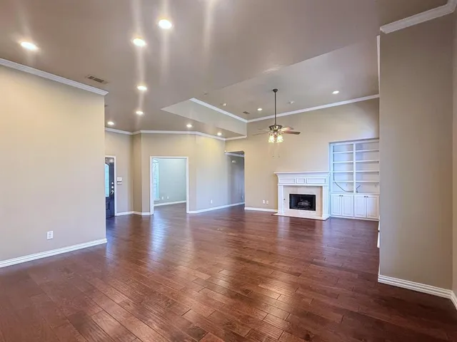 an empty room with wooden floor fireplace and windows