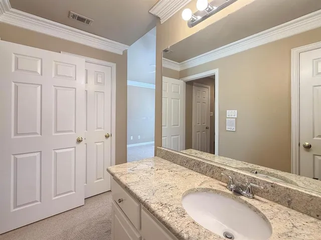 a bathroom with a granite countertop double vanity sink and mirror