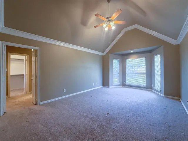a view of an empty room with chandelier fan