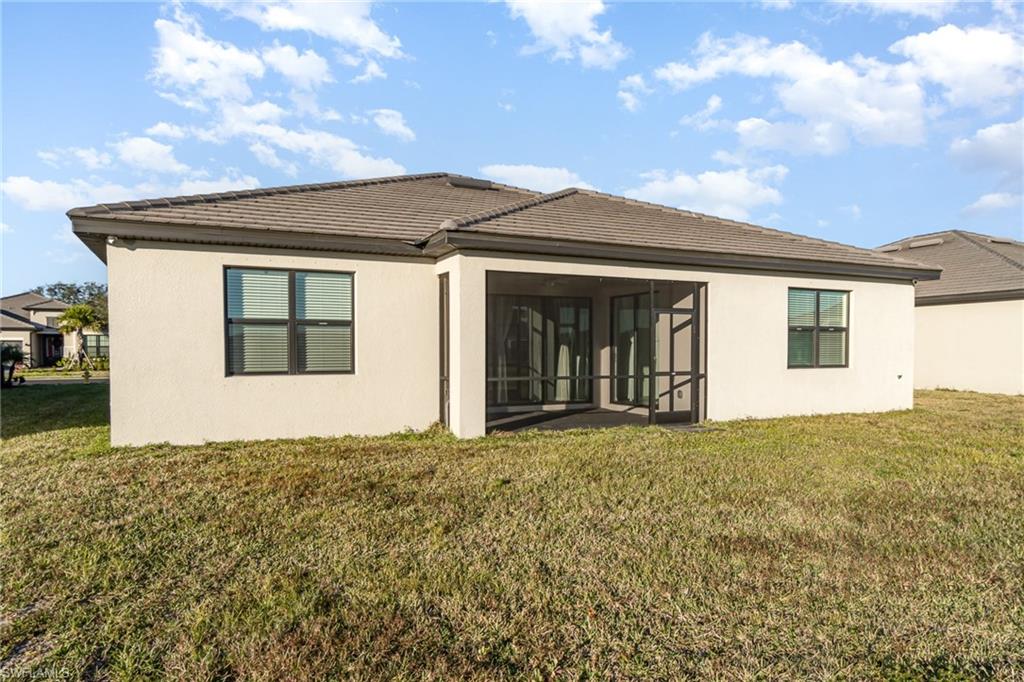 11127 Canopy Loop Fort Myers, FL 33913 - Photo 15 of 29 Back of house with stucco siding, a lawn, and a sunroom