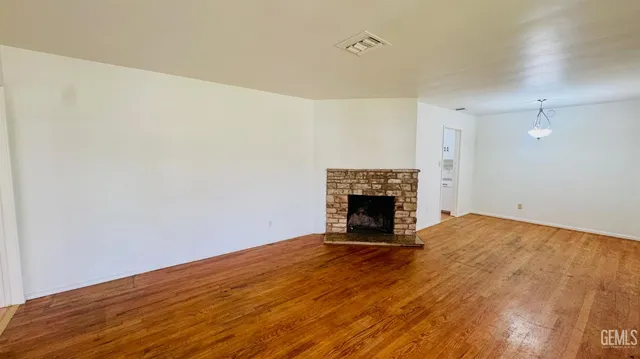 a view of an empty room with wooden floor and a fireplace