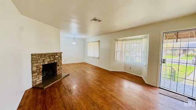 a view of empty room with wooden floor and fireplace