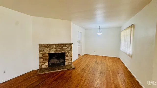a view of empty room with wooden floor and fireplace