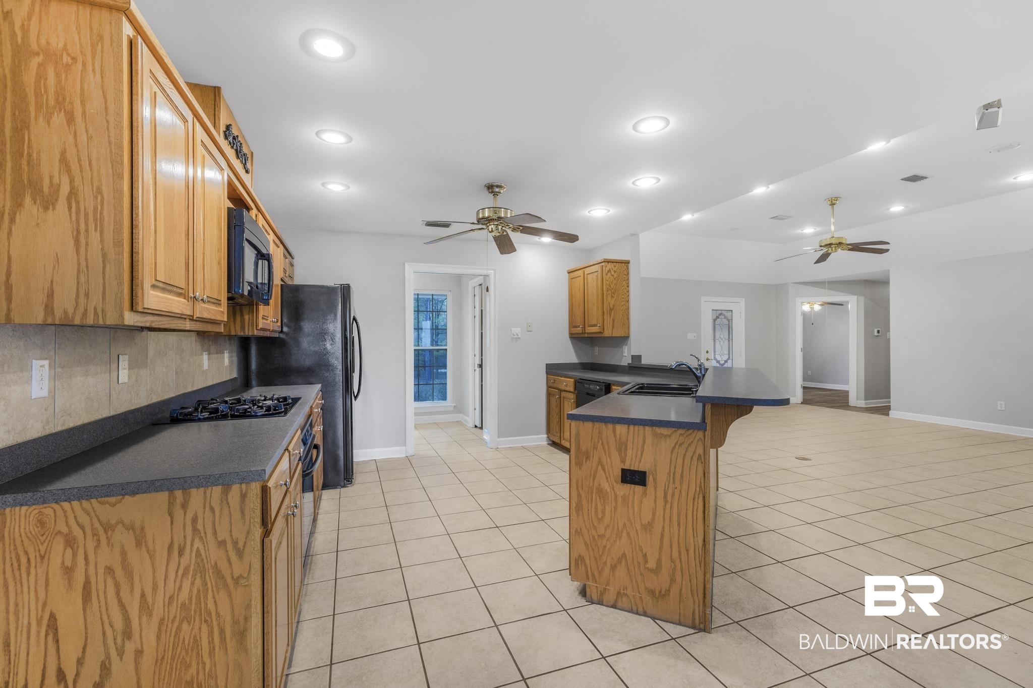 8077 Hooks Road Bay Minette, AL 36507 - Photo 10 of 48 Kitchen with a peninsula, dark countertops, light tile patterned floors, a breakfast bar, and recessed lighting