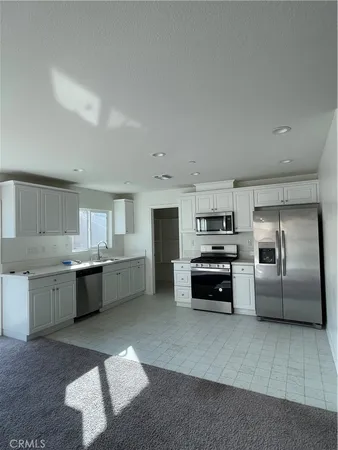 a kitchen with granite countertop a refrigerator and white cabinets