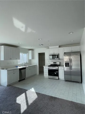a kitchen with granite countertop a refrigerator and white cabinets