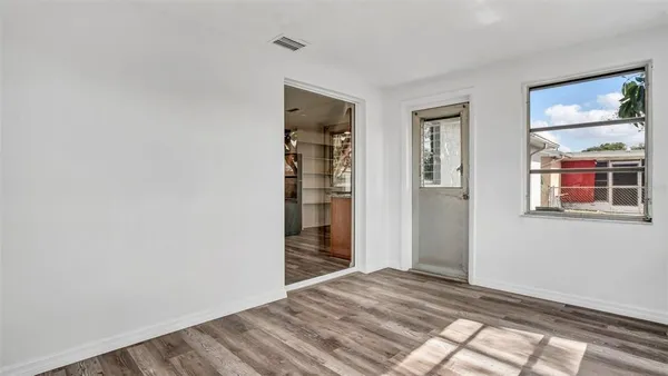a view of an empty room with wooden floor and a window