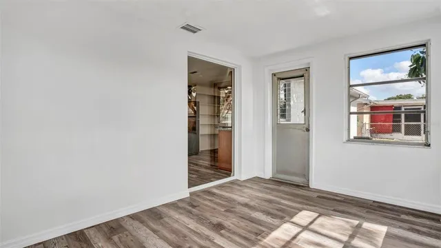 a view of an empty room with wooden floor and a window