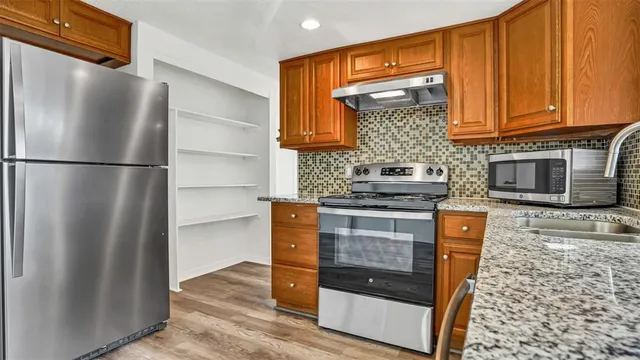 a kitchen with stainless steel appliances granite countertop a refrigerator and a stove top oven