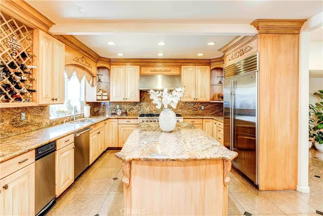 a large kitchen with stainless steel appliances kitchen island granite countertop a refrigerator and a sink