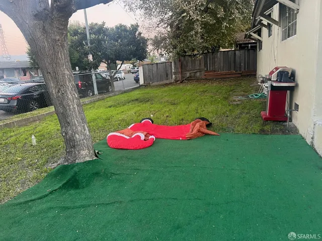 a view of a backyard with table and chairs potted plants and large tree