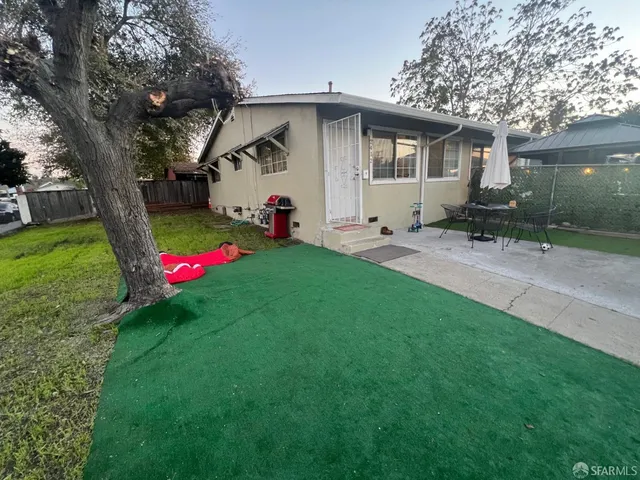a view of a white house with a yard and a large tree