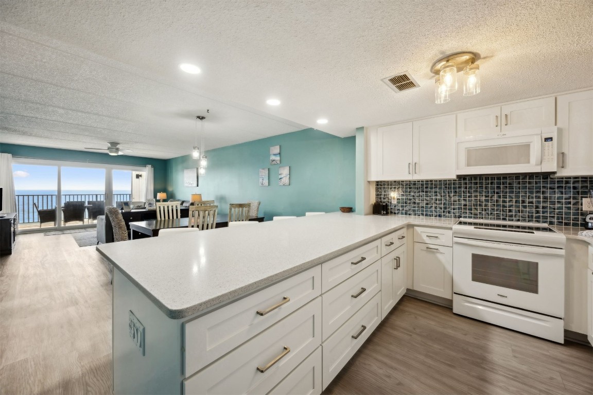 3350 South Fletcher Avenue, Unit 5D Fernandina Beach, FL 32034 - Photo 11 of 48 a large white kitchen with wooden floor and stainless steel appliances
