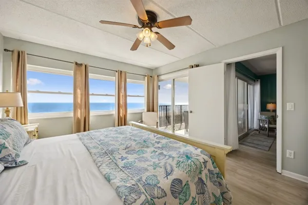 a bedroom with a bed ceiling fan and a wooden floor