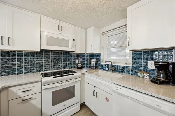 a large white kitchen with wooden floor and stainless steel appliances