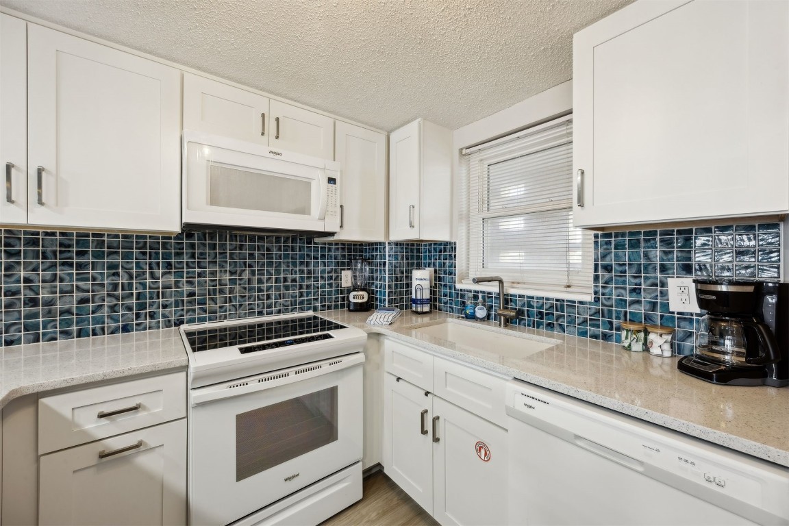 3350 South Fletcher Avenue, Unit 5D Fernandina Beach, FL 32034 - Photo 10 of 48 a kitchen with granite countertop white cabinets and white appliances