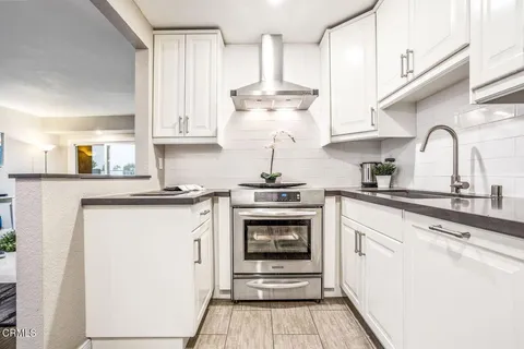 a kitchen with stainless steel appliances granite countertop a stove a sink and white cabinets