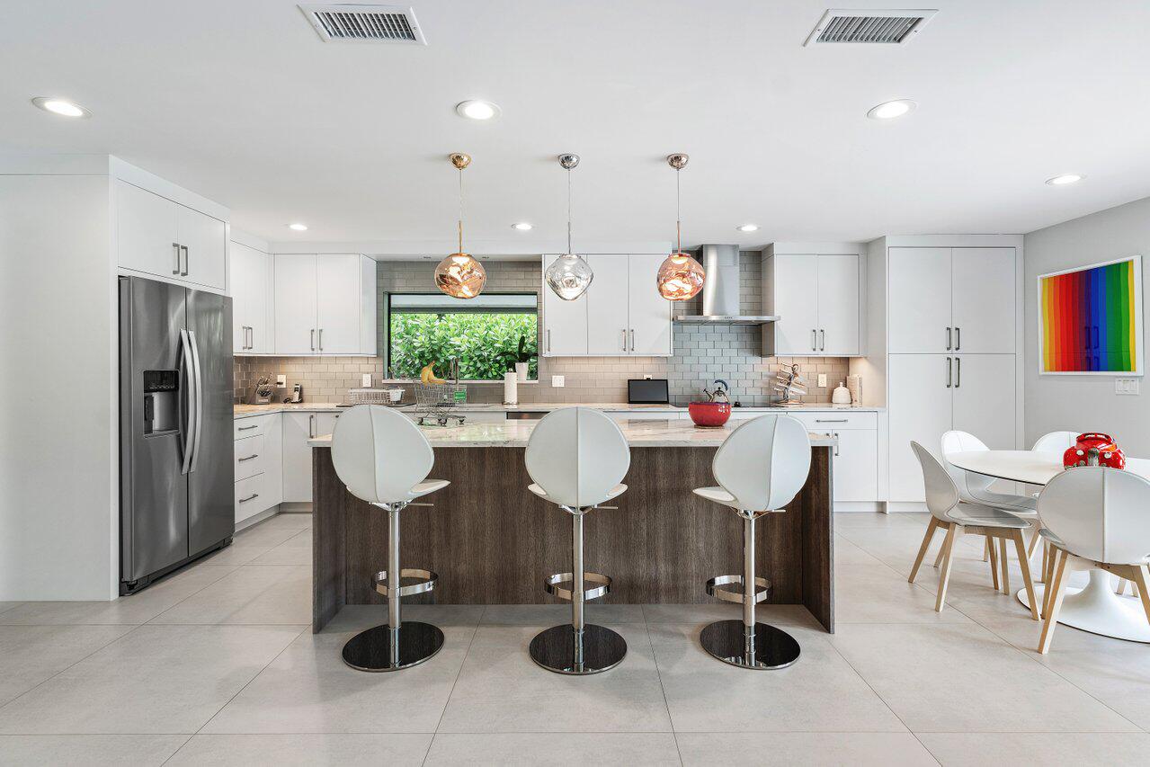 3707 Red Maple Circle Delray Beach, FL 33445 - Photo 14 of 39 a kitchen with stainless steel appliances kitchen island granite countertop a table and chairs in it