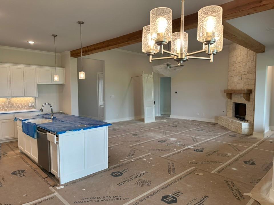 410 Cobb Road Leonard, TX 75452 - Photo 11 of 24 Open-concept living space featuring a stone fireplace with a substantial wood mantel, exposed ceiling beams, and a modern chandelier