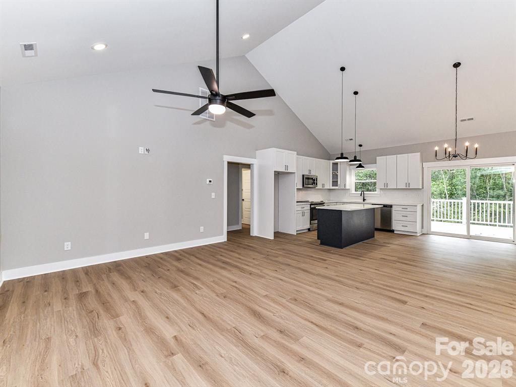 6720 Jesse Rushing Road Marshville, NC 28103 - Photo 8 of 28 a view of a kitchen with a stove wooden floor and a ceiling fan
