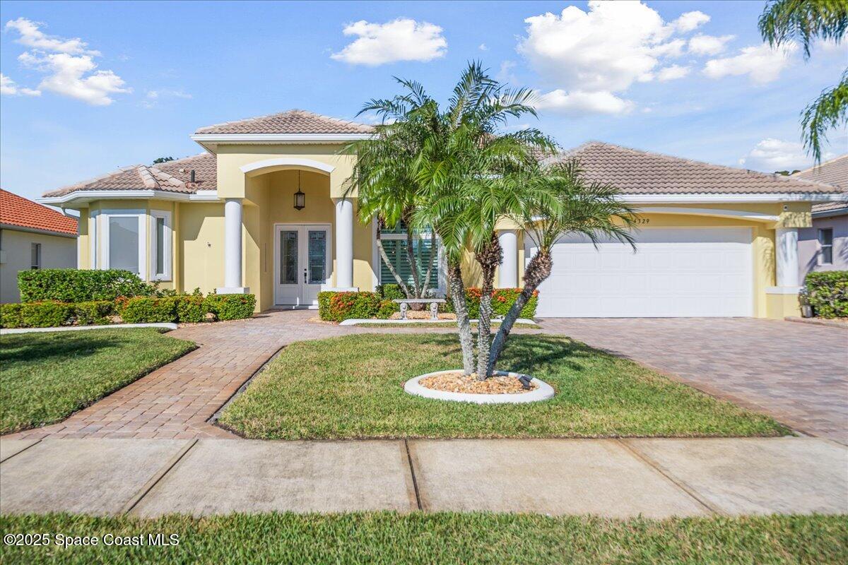 a front view of a house with a yard and palm trees